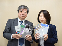 海渡座長（左）と石田事務局長　過去の審査を記録として取りまとめた書籍を手に